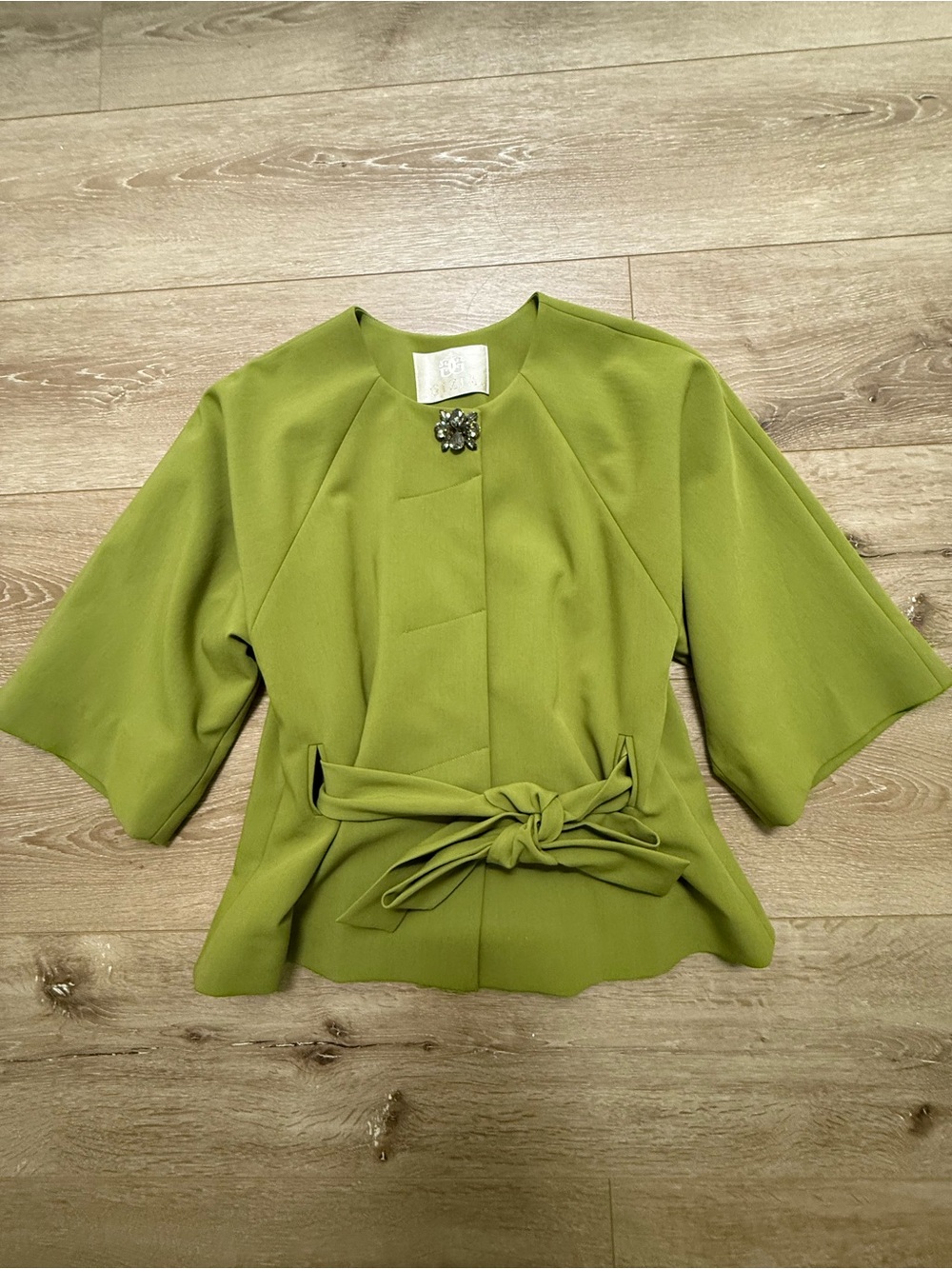 Short sleeve tie front jacket with a jewel encrusted collar clasp .